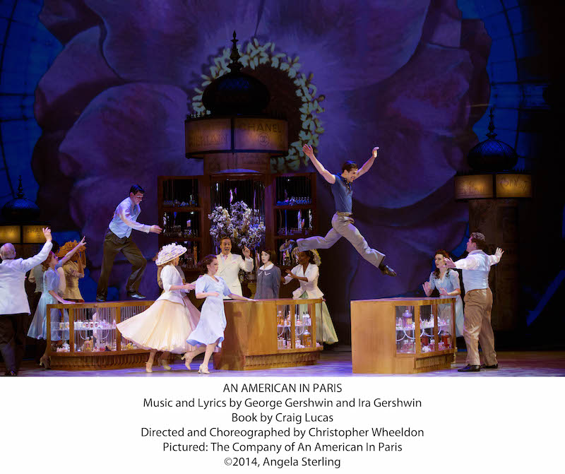The cast of An American Paris with Robert Fairchild leapig off a table